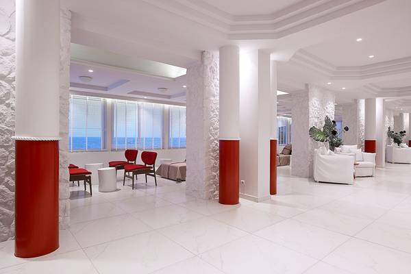 Innenbereich des Dimitra Beach Hotel & Suites mit weißen Böden, roten Säulen und Blick aufs Meer