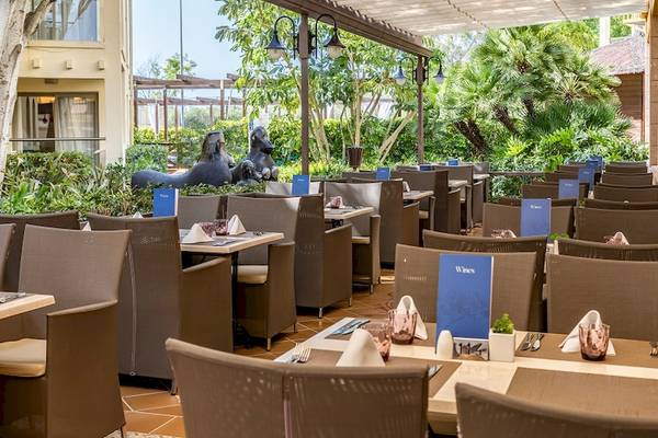 Gartenrestaurant des Zafiro Tropic Hotels mit Tischen, Stühlen und Weinkarten draußen.