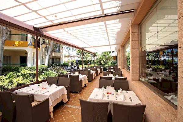 Außenterrasse des Zafiro Tropic Hotels mit gedeckten Tischen und Stühlen.