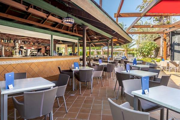 Außenterrasse des Zafiro Tropic Hotels mit Tischen, Stühlen und einer Bar.