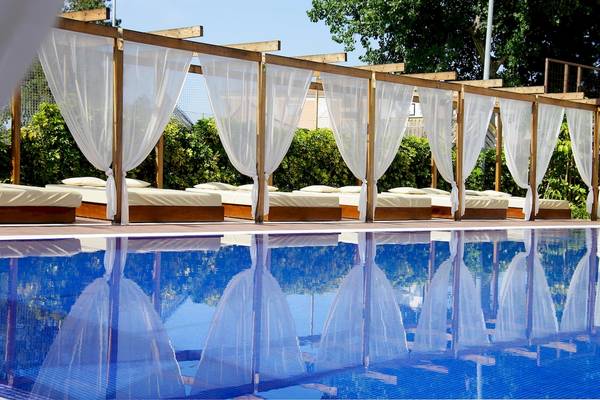 Pool-Lounge-Bereich im Zafiro Tropic Hotel mit betten unter weißen Vorhängen.