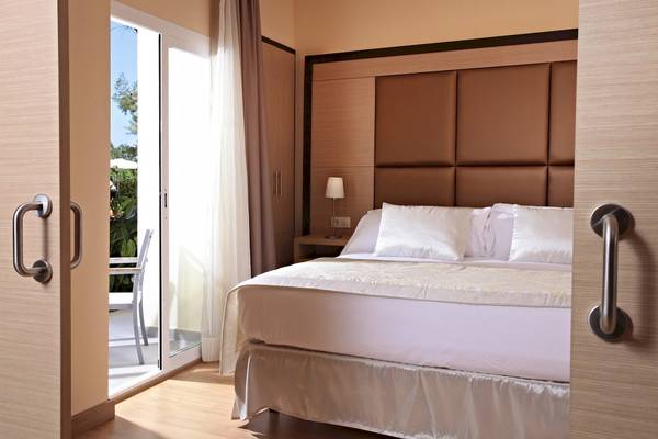 Schlafzimmer im Zafiro Tropic Hotel mit Bett, Nachttisch und offenem Glastürbalkon.
