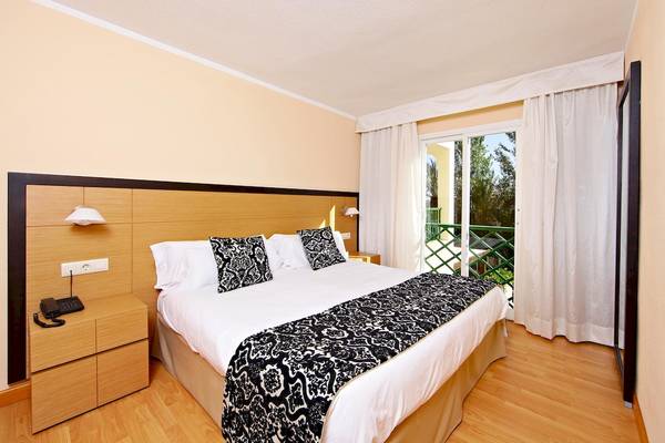 Hotelzimmer mit Doppelbett, Balkon und Ausblick auf Bäume im Zafiro Tropic Hotel.
