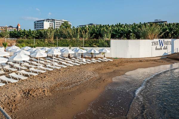 Strand des White City Resort mit vielen Liegen und Sonnenschirmen am Meer