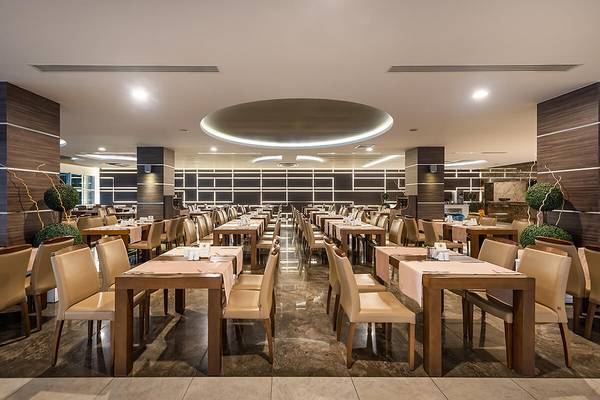 Innenansicht des Restaurants im White City Resort mit runden Tischen und Bänken.