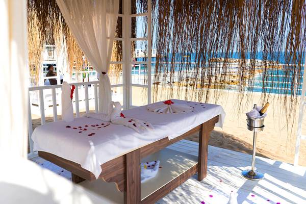 Massagetisch im White City Resort mit Blick auf den Strand, geschmückt mit Blumenblättern und einer Flasche Champagner.