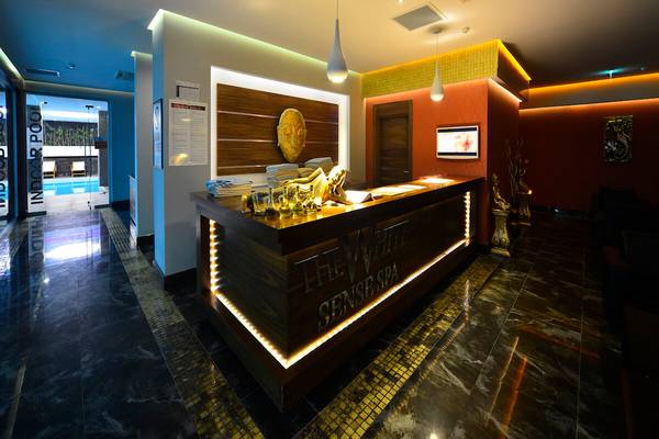 Empfangsbereich des White City Resorts mit goldenen Akzenten und Holzelementen.
