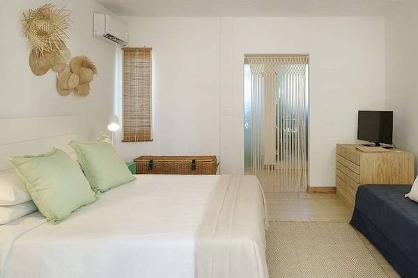 Schlafzimmer im The Ravenala Attitude Hotel mit weißen Wänden, einem großen Bett, grünen Kissen und einer Couch.