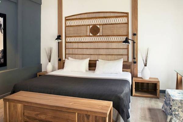 Ein modernes Hotelzimmer mit einem großen Bett, einem hölzernen Kopfteil, zwei Nachttischen und einer Gemäldewand.