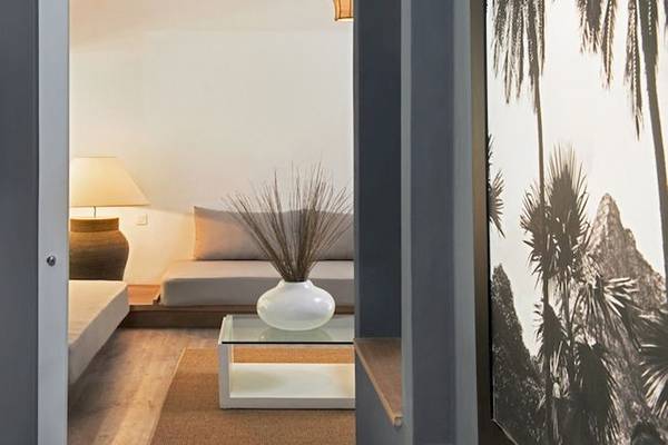 Innenansicht eines Zimmers im Hotel The Ravenala Attitude mit Fernseher, Lampe und Palmenbild.
