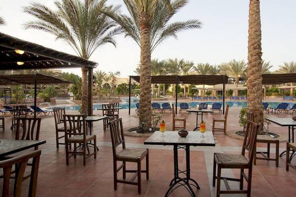 Außenbereich des Jaz Solaya Hotels mit Tischen, Stühlen und Palmen neben einem Pool.