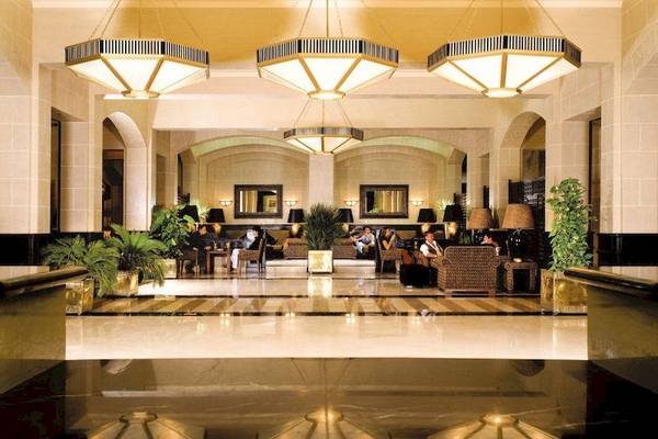 Lobby des Jaz Solaya Hotels mit gemusterten Kronleuchtern und Gästen, die sich entspannen.