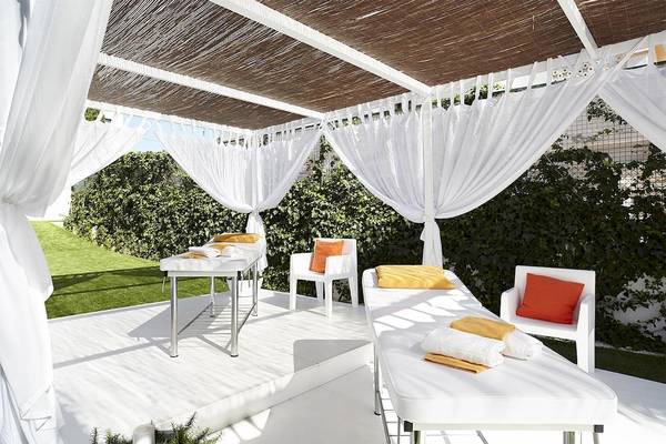 Massagebereich auf der Terrasse der Ibiza Sun Apartments, mit weißen Möbeln und Kissen.