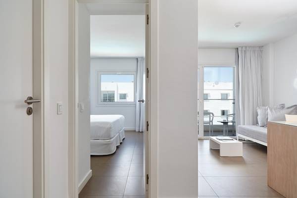 Innenansicht eines Zimmers der Ibiza Sun Apartments mit modernem Design und Blick auf einen Balkon.