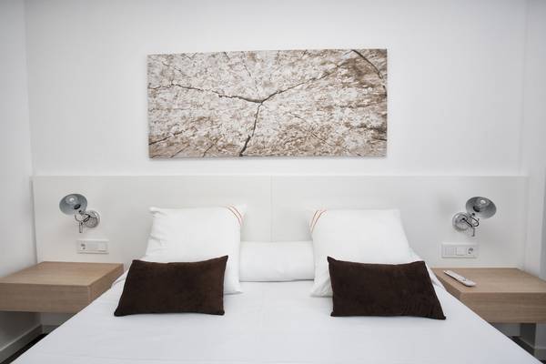 Ein Hotelzimmer mit einem Doppelbett, weißen Kissen, braunen Kissen und einer Wand mit einer großen, gerahmten Kunst.