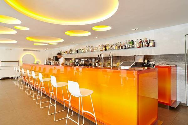 Hotellobby mit orangefarbener Bar und weißen Stühlen