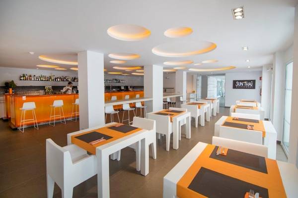 Innenansicht eines Restaurants mit orangenen Stühlen und runden Leuchten an der Decke, servierbar vorbereitete Tische.