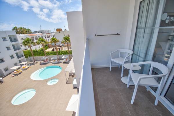 Balkon mit Poolblick im Ibiza Sun Apartments, inklusive weißer Möbel und Palmen im Hintergrund.