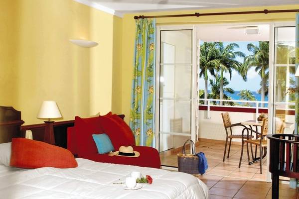 Zimmer mit Balkon im Hotel Pierre & Vacances Village Sainte Luce mit Blick auf das Meer und Palmen.