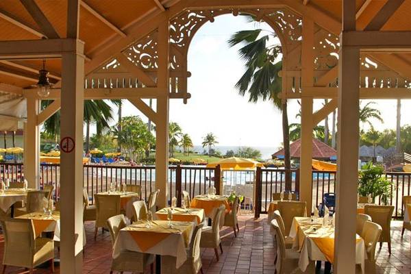 Terrasse eines Hotels mit gedeckten Tischen und Stühlen, die einen Blick auf den Pool und das Meer bieten.