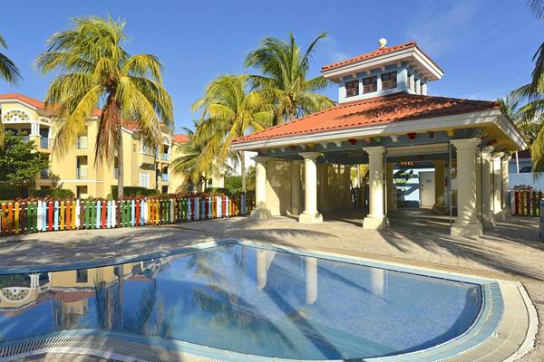 Ein Swimmingpool vor dem Hotel Iberostar Playa Alameda, umgeben von bunten Zäunen und Palmen.