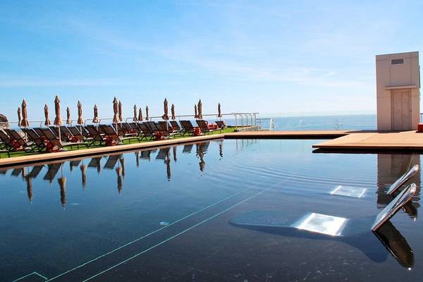 Poolterrasse des Riviera Vista Hotels mit Sonnenliegen und Schirmen am Meer