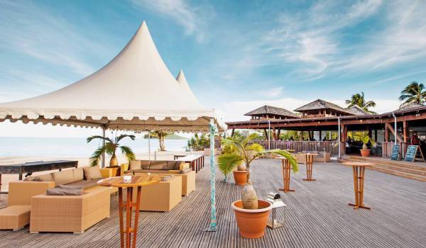 Langley Resort Fort Royal Strandbar mit weißem Zelt, Sofas und Tischen auf der Terrasse