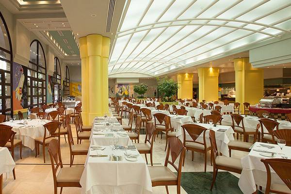 Innenbereich des Lopesan Costa Meloneras Resorts & Spa Restaurant mit gedeckten Tischen und Stühlen.