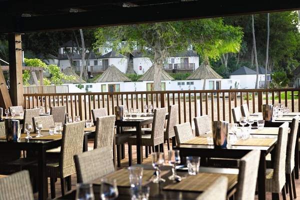 Innenansicht des Restaurants im Langley Resort Fort Royal mit mehreren gedeckten Tischen und Blick auf die Hotelanlage im Hintergrund.