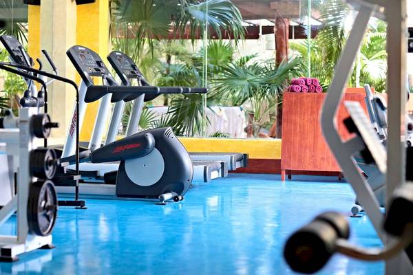 Fitnessstudio im Bahia Principe Luxury Akumal mit Laufbändern und Hanteln.