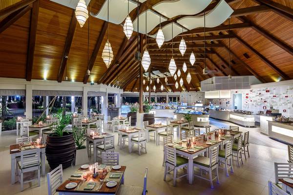 Innenbereich des Kurumba Maldives Hotels mit Restaurantbereich, Tischen und Stühlen.