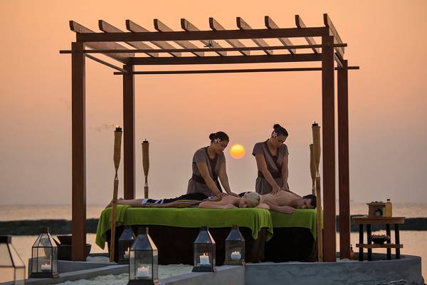 Massage unter einem Pavillon am Strand im Kurumba Maldives bei Sonnenuntergang.