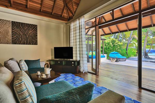 Wohnzimmer im Kurumba Maldives mit offenem Fenster und Blick auf den Ozean.