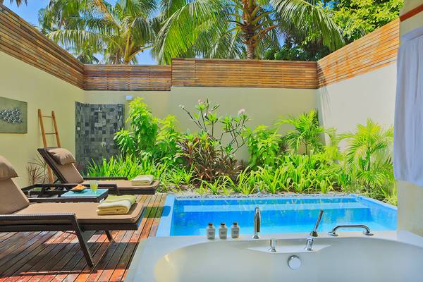 Außenpool und Terrasse im Kurumba Maldives Hotel mit Loungestühlen und Pflanzen.