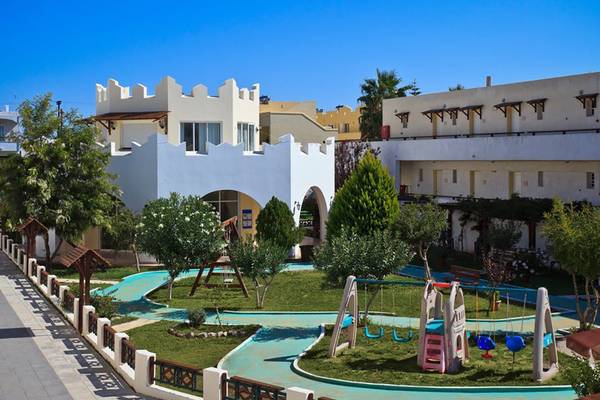 Außenbereich des Gaia Village Hotels mit Gebäuden, Bäumen und Spielplatz