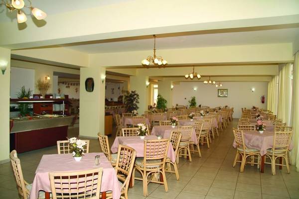 Innenansicht des Restaurants im Gaia Village Hotel mit vielen gedeckten Tischen und Blumenarrangements.