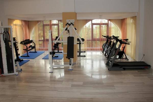 Fitnessraum im Hotel Gaia Village mit verschiedenen Trainingsgeräten und freien Fenstern.