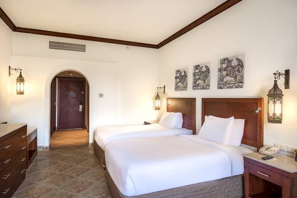 Zimmer im Hilton Marsa Alam Nubian Resort mit zwei Betten, Dekor und Möbeln.