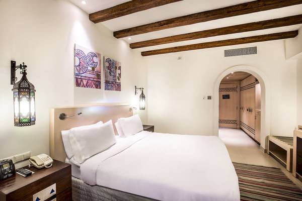 Schlafzimmer im Hilton Marsa Alam Nubian Resort mit einem Bett, Nachttischen und Wandkunst.