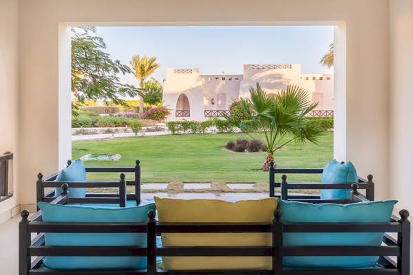 Aussicht von der Terrasse des Hilton Marsa Alam Nubian Resort auf einen gepflegten Rasen und Gebäude