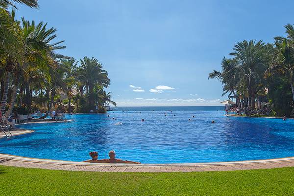 Außenpool des Lopesan Costa Meloneras Resort & Spa mit Palmen und Blick auf das Meer.