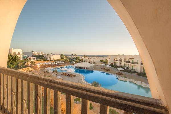 Aussicht auf den Pool des Hilton Marsa Alam Nubian Resort mit Sonnenliegen und Sonnenschirmen.