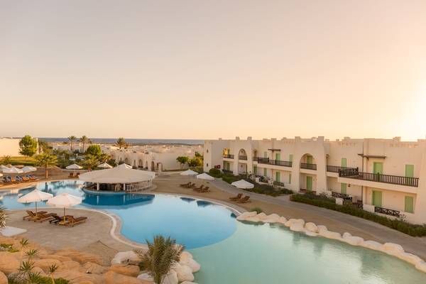 Außenbereich des Hilton Marsa Alam Nubian Resort mit Swimmingpool, Lounge-Liegen und Sonnenschirmen.