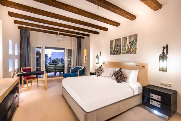 Innenansicht eines Zimmers im Hilton Marsa Alam Nubian Resort mit Bett, Schreibtisch, Stühlen und Dekoration.