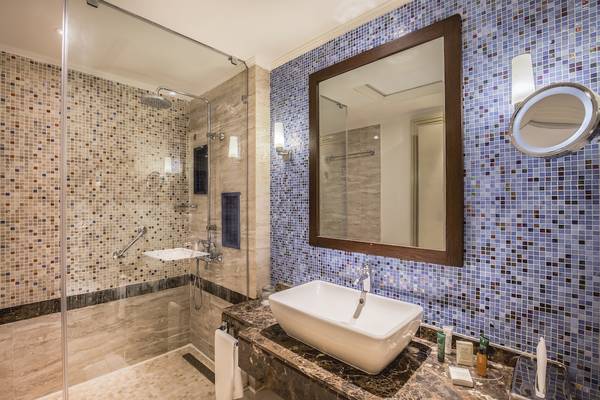 Badezimmer im Hilton Marsa Alam Nubian Resort mit blauen Wandfliesen, Glasdusche und Waschbecken.