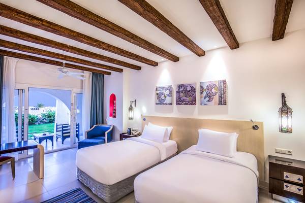 Doppelzimmer im Hilton Marsa Alam Nubian Resort mit zwei Betten, Schreibtisch und Terrasse.
