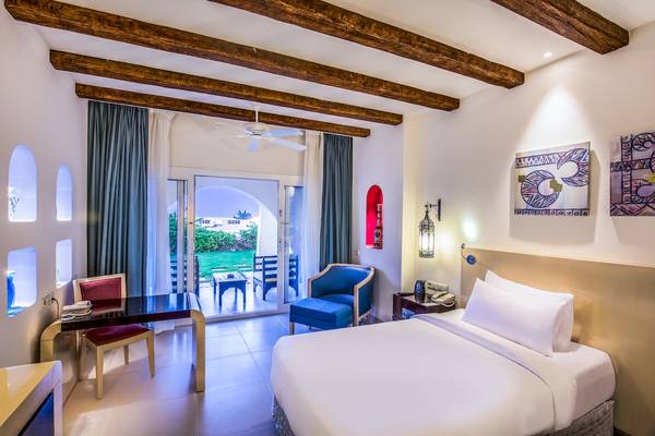 Innenansicht eines Hotelzimmers im Hilton Marsa Alam Nubian Resort mit Bett, Schreibtisch und offenem Balkon.