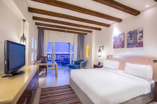 Hotelzimmer im Hilton Marsa Alam Nubian Resort mit Fernseher, Bett, Möbeln und Balkon.