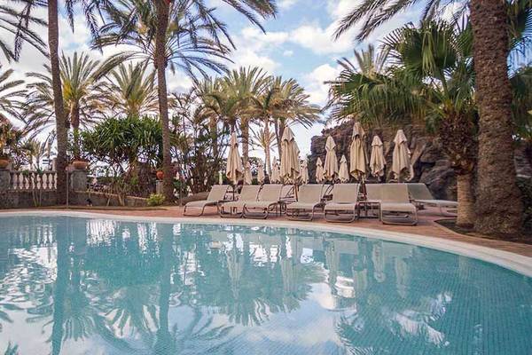 Außenpoolbereich des Lopesan Costa Meloneras Resort mit weißen Sonnenliegen und Palmen