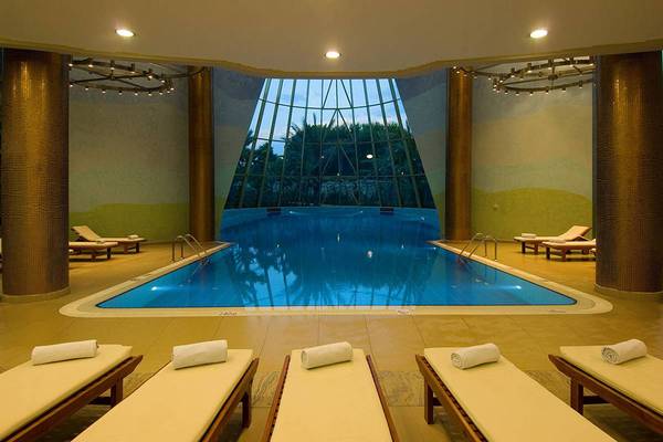 Innenpoolbereich des Blue Waters Club Hotels mit Liegestühlen und Glasdach.